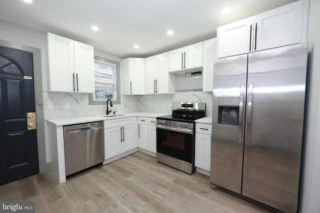 1357 E Sedgley Ave, Philadelphia, PA 19134 - kitchen with appliances with stainless steel finishes, a sink, white cabinetry, decorative backsplash, and light wood-style floors