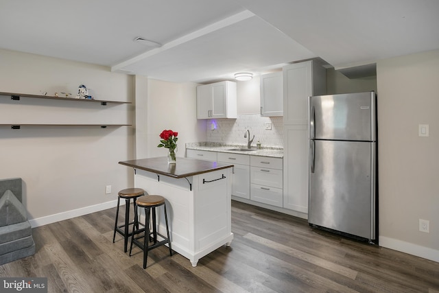 6001 Kroy Ct, Springfield, VA 22150 - kitchen with freestanding refrigerator, dark wood-type flooring, decorative backsplash, a breakfast bar area, and white cabinets