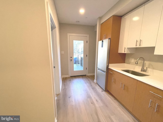 1307 K St SE Unit 101, Washington, DC 20003 - kitchen featuring a sink, freestanding refrigerator, light wood-style flooring, light countertops, and baseboards