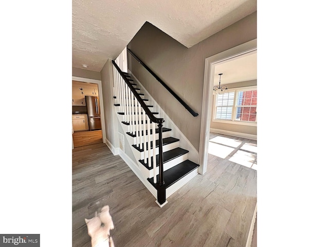 1045 S Bradford St, Dover, DE 19904 - stairway featuring a textured ceiling, a chandelier, and wood finished floors