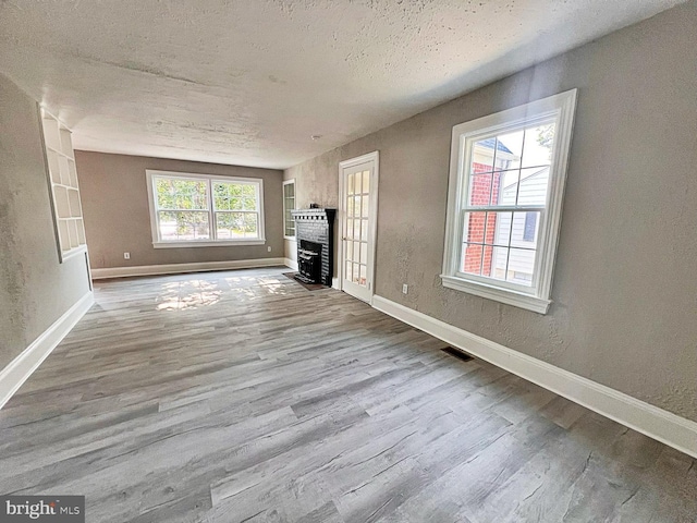 1045 S Bradford St, Dover, DE 19904 - unfurnished living room featuring wood finished floors, a fireplace with flush hearth, and a textured wall