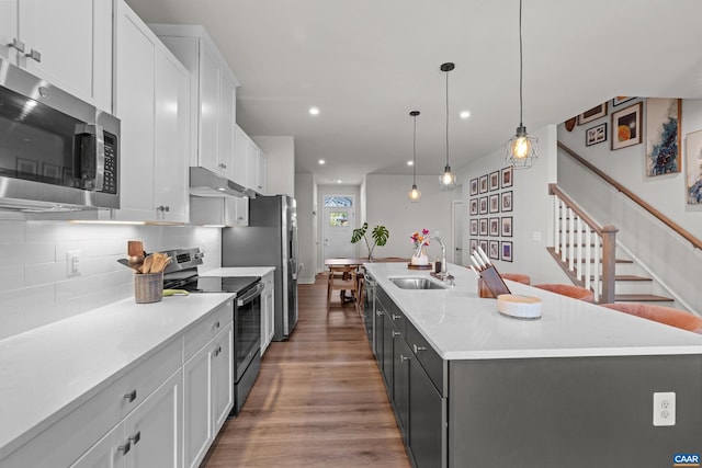 820 Swede St, Charlottesville, VA 22901 - kitchen featuring appliances with stainless steel finishes, a sink, wood finished floors, an island with sink, and white cabinetry