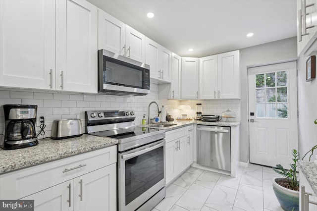 2174 E Oakdale St, Philadelphia, PA 19125 - kitchen featuring appliances with stainless steel finishes, white cabinetry, light marble finish floors, light stone counters, and recessed lighting