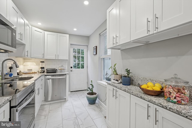 2174 E Oakdale St, Philadelphia, PA 19125 - kitchen with stainless steel appliances, recessed lighting, white cabinetry, decorative backsplash, and light marble finish floors