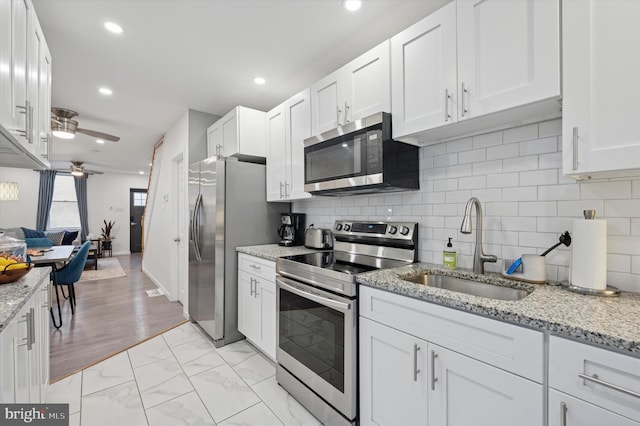 2174 E Oakdale St, Philadelphia, PA 19125 - kitchen featuring appliances with stainless steel finishes, a ceiling fan, white cabinetry, backsplash, and light marble finish flooring