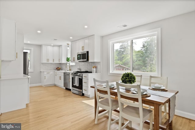 418 Belton Ct, Silver Spring, MD 20901 - kitchen with appliances with stainless steel finishes, white cabinetry, light wood-style floors, decorative backsplash, and light countertops