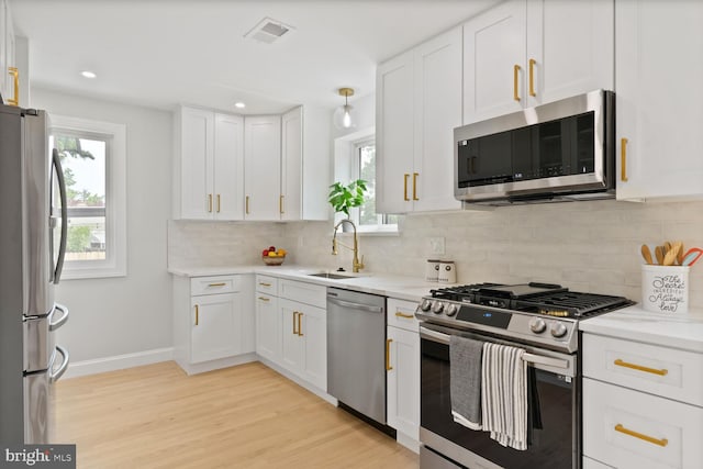 418 Belton Ct, Silver Spring, MD 20901 - kitchen with stainless steel appliances, white cabinetry, light wood-type flooring, a sink, and recessed lighting