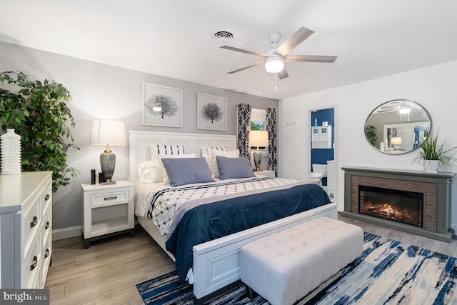 44 Creek Rd, Newville, PA 17241 - bedroom featuring light wood-type flooring, a glass covered fireplace, connected bathroom, baseboards, and a ceiling fan