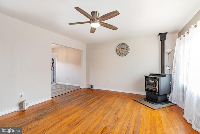 1503 Shirley Ave, Carlisle, PA 17013 - unfurnished living room featuring a wood stove, ceiling fan, light wood-style flooring, and baseboards