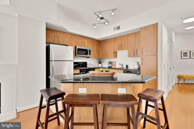 1021 N Garfield St Unit B37, Arlington, VA 22201 - kitchen with appliances with stainless steel finishes, a sink, a breakfast bar, and light wood-style floors