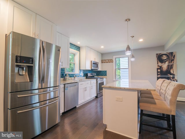 2509 Mason St, Silver Spring, MD 20902 - kitchen with appliances with stainless steel finishes, dark wood-type flooring, white cabinets, a kitchen island, and plenty of natural light