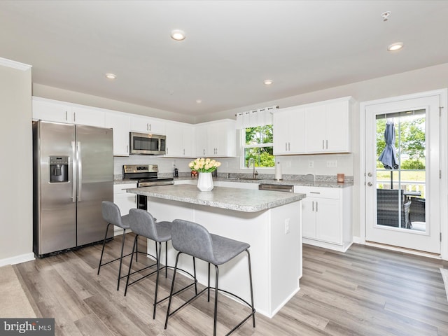 38 Herman Gaver Pl, Hagerstown, MD 21740 - kitchen with stainless steel appliances, a kitchen island, light wood-style flooring, white cabinetry, and a breakfast bar area