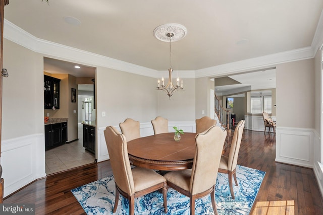 21550 Wild Timber Ct, Broadlands, VA 20148 - dining room featuring a chandelier, dark wood-style floors, a wainscoted wall, ornamental molding, and a decorative wall