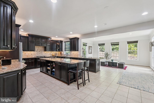 21550 Wild Timber Ct, Broadlands, VA 20148 - kitchen featuring light tile patterned floors, backsplash, crown molding, light stone countertops, and a breakfast bar