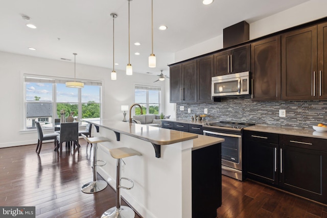 1107 S Walter Reed Dr S Unit 502, Arlington, VA 22204 - kitchen featuring stainless steel appliances, dark wood-type flooring, decorative backsplash, light countertops, and a kitchen bar