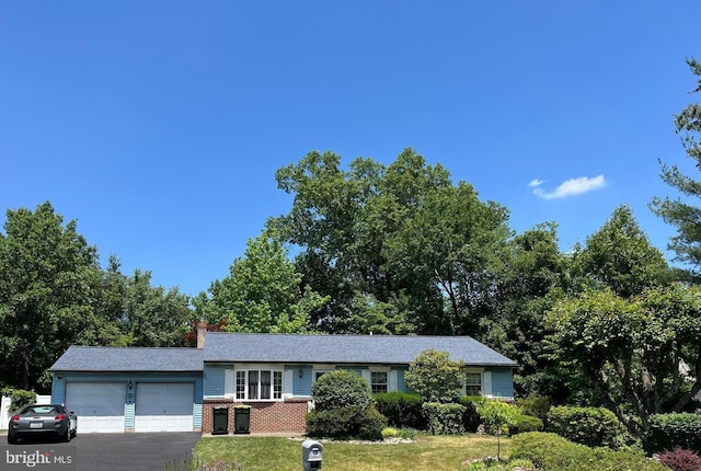 2545 Pioneer Rd, Hatboro, PA 19040 - view of front of property featuring an attached garage, brick siding, a front lawn, asphalt driveway, and a chimney