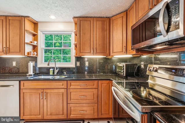14616 Orangewood St, Silver Spring, MD 20905 - kitchen featuring appliances with stainless steel finishes, open shelves, a sink, brown cabinetry, and a textured ceiling