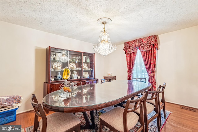 14616 Orangewood St, Silver Spring, MD 20905 - dining space featuring a chandelier, wood finished floors, baseboards, and a textured ceiling