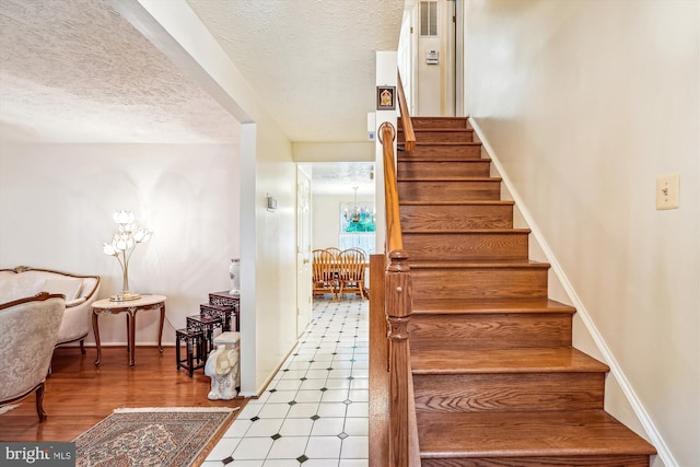 14616 Orangewood St, Silver Spring, MD 20905 - stairs featuring a chandelier, a textured ceiling, tile patterned floors, and baseboards