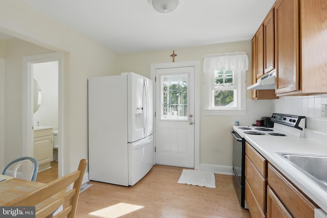 1022 S Beechfield Ave, Baltimore, MD 21229 - kitchen featuring white appliances, under cabinet range hood, brown cabinetry, light wood-style floors, and light countertops
