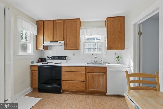 1022 S Beechfield Ave, Baltimore, MD 21229 - kitchen with white dishwasher, range with electric cooktop, under cabinet range hood, a sink, and tasteful backsplash