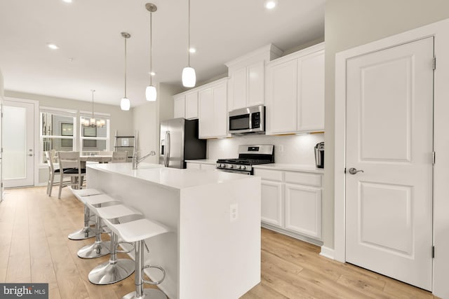2521 River Terrace Rd, Hyattsville, MD 20782 - kitchen featuring appliances with stainless steel finishes, a kitchen island with sink, white cabinets, a kitchen bar, and light wood-style floors