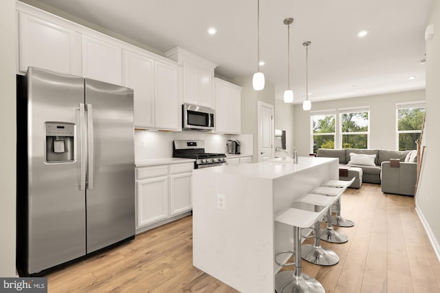 2521 River Terrace Rd, Hyattsville, MD 20782 - kitchen with appliances with stainless steel finishes, light wood-type flooring, white cabinetry, a breakfast bar area, and a center island with sink