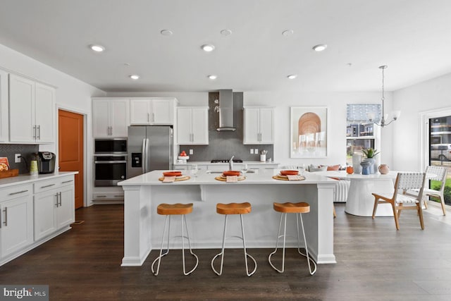 453 Ensemble Way, Frederick, MD 21701 - kitchen with stainless steel appliances, wall chimney exhaust hood, white cabinets, decorative backsplash, and a kitchen breakfast bar