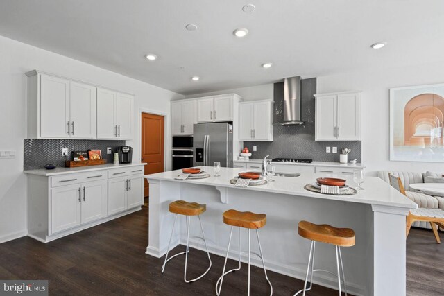 453 Ensemble Way, Frederick, MD 21701 - kitchen with wall chimney range hood, appliances with stainless steel finishes, decorative backsplash, white cabinets, and a breakfast bar area