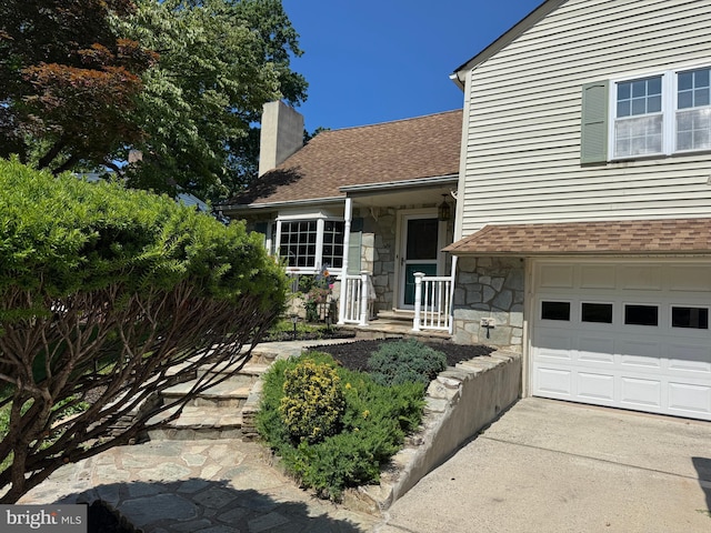 129 Redwood Ave, Trenton, NJ 08619 - doorway to property with a chimney, stone siding, a shingled roof, and a garage
