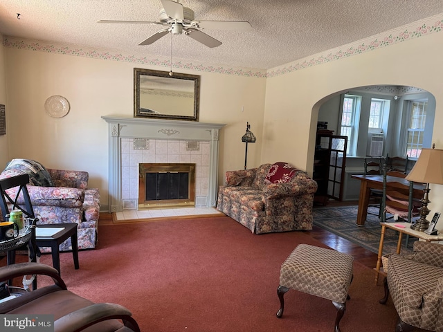 129 Redwood Ave, Trenton, NJ 08619 - carpeted living room featuring arched walkways, a textured ceiling, a ceiling fan, and a tile fireplace