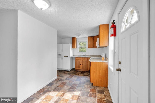 70 Steinfeld Ave, Pittsgrove, NJ 08318 - kitchen featuring white appliances, a textured ceiling, brown cabinets, light countertops, and dark stone finish floors