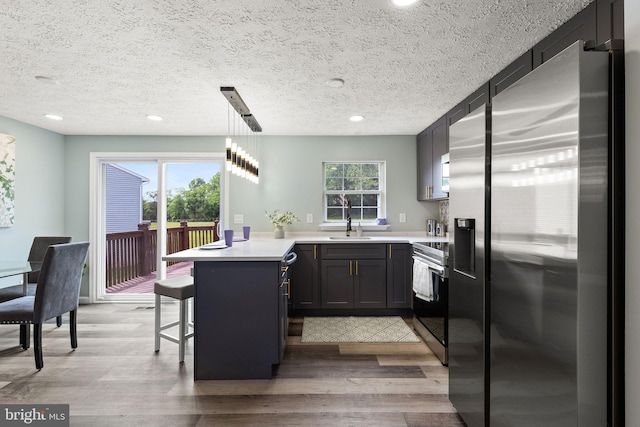 1207 Blithe Ct, Upper Marlboro, MD 20774 - kitchen featuring stainless steel appliances, a peninsula, a sink, light wood-style floors, and a textured ceiling