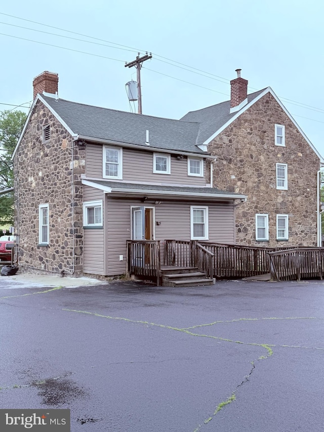 2410 Chichester Ave, Upper Chichester, PA 19061 - rear view of house featuring stone siding, a chimney, and a wooden deck