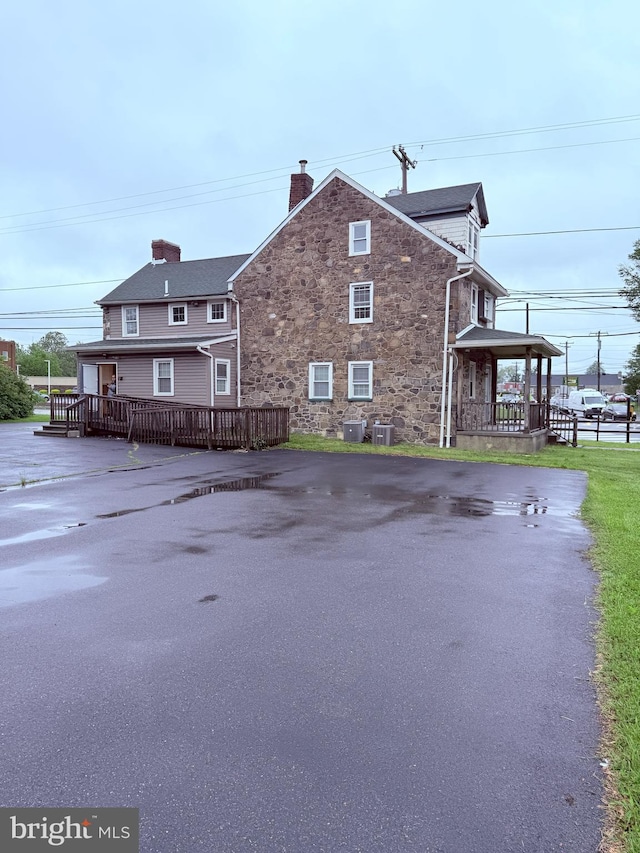 2410 Chichester Ave, Upper Chichester, PA 19061 - view of home's exterior featuring stone siding, central air condition unit, and a chimney