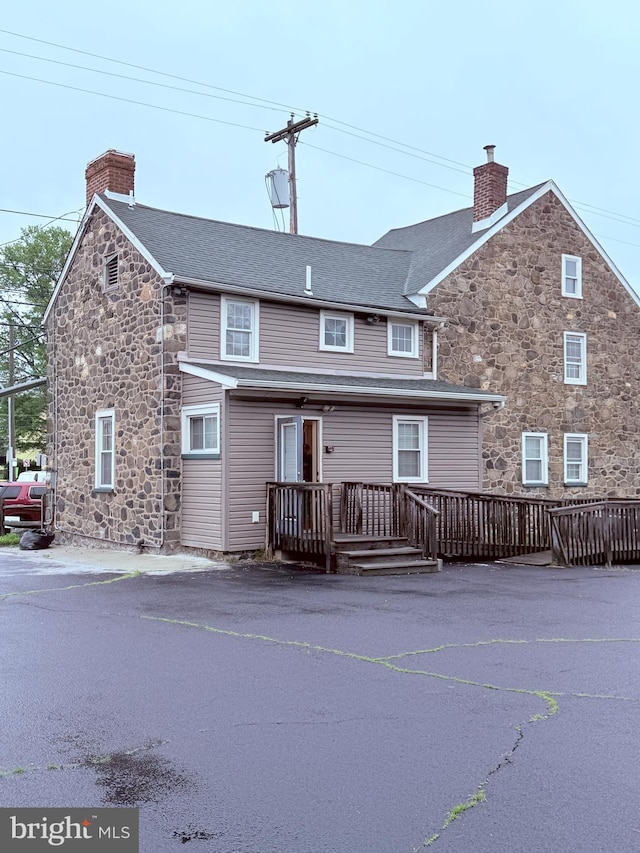 2410 Chichester Ave, Upper Chichester, PA 19061 - rear view of property featuring stone siding, a chimney, and a wooden deck