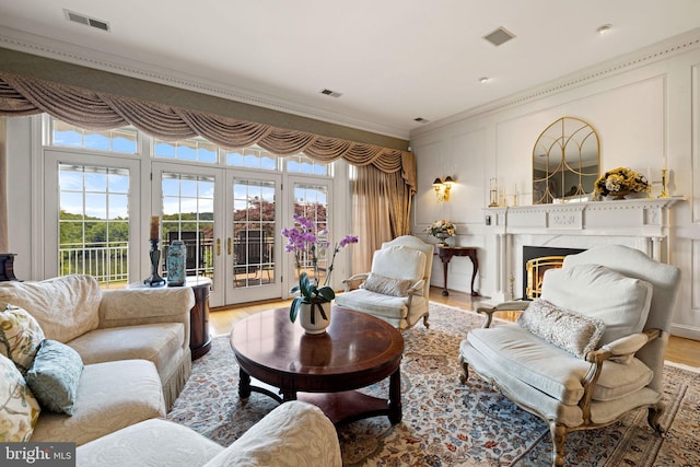 77 Lionheart Ter, Falling Waters, WV 25419 - living area featuring light wood-style floors, ornamental molding, french doors, a high end fireplace, and a decorative wall