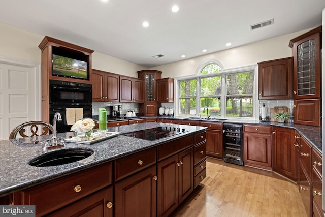 77 Lionheart Ter, Falling Waters, WV 25419 - kitchen featuring beverage cooler, black appliances, tasteful backsplash, dark stone counters, and glass insert cabinets