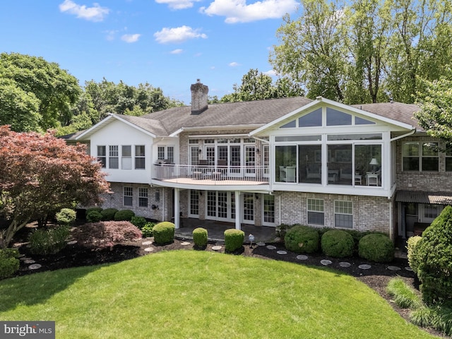 77 Lionheart Ter, Falling Waters, WV 25419 - rear view of house featuring a chimney, a yard, a patio, brick siding, and a sunroom
