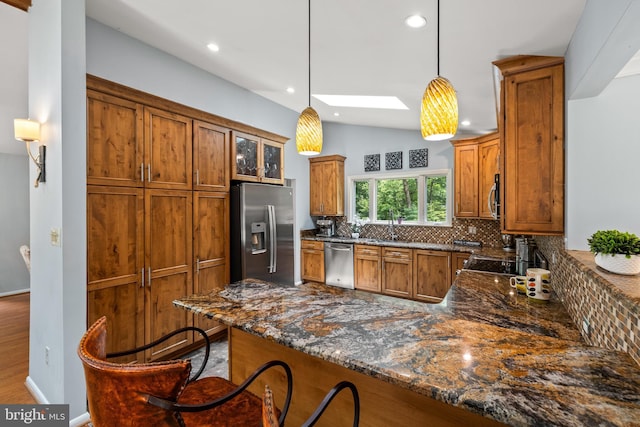 2404 Sugarberry Ct, Reston, VA 20191 - kitchen featuring appliances with stainless steel finishes, brown cabinetry, tasteful backsplash, vaulted ceiling, and dark stone counters