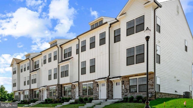 338 Ensemble Way, Frederick, MD 21701 - townhome / multi-family property with board and batten siding, central AC unit, stone siding, and a front lawn
