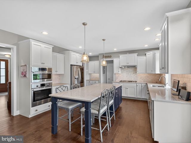 548 E Delp Rd, Lancaster, PA 17601 - kitchen featuring stainless steel appliances, a center island, under cabinet range hood, white cabinetry, and decorative backsplash