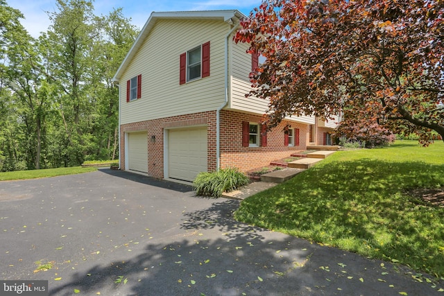 129 Deck Rd, Womelsdorf, PA 19567 - view of property exterior featuring brick siding, asphalt driveway, a garage, and a yard
