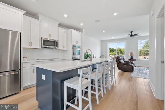 8790 Kensington Church St, Manassas, VA 20112 - kitchen featuring appliances with stainless steel finishes, a kitchen island with sink, light wood finished floors, a breakfast bar area, and a sink