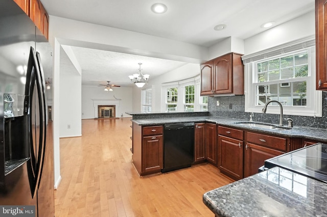 2240 Halter Ln, Reston, VA 20191 - kitchen with black appliances, a chandelier, light wood-style floors, decorative backsplash, and a peninsula