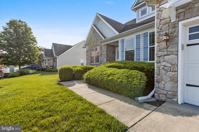 31746 Chablis Ln Unit 71, Lewes, DE 19958 - view of front facade featuring stone siding, a front yard, and a shingled roof