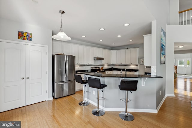 31746 Chablis Ln Unit 71, Lewes, DE 19958 - kitchen featuring appliances with stainless steel finishes, a peninsula, dark countertops, a breakfast bar area, and light wood-style flooring