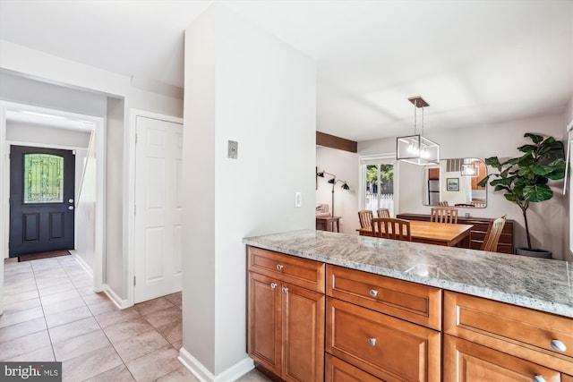 10105 Meredith Ave, Silver Spring, MD 20910 - kitchen featuring light tile patterned flooring, light stone counters, brown cabinetry, hanging light fixtures, and baseboards
