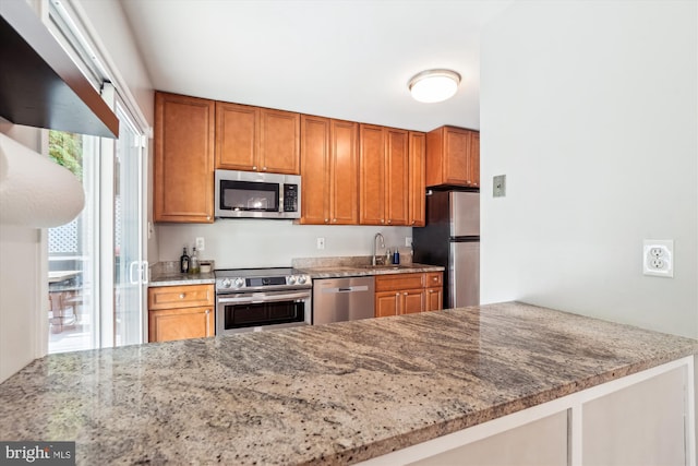 10105 Meredith Ave, Silver Spring, MD 20910 - kitchen featuring appliances with stainless steel finishes, light stone countertops, a sink, brown cabinets, and a peninsula