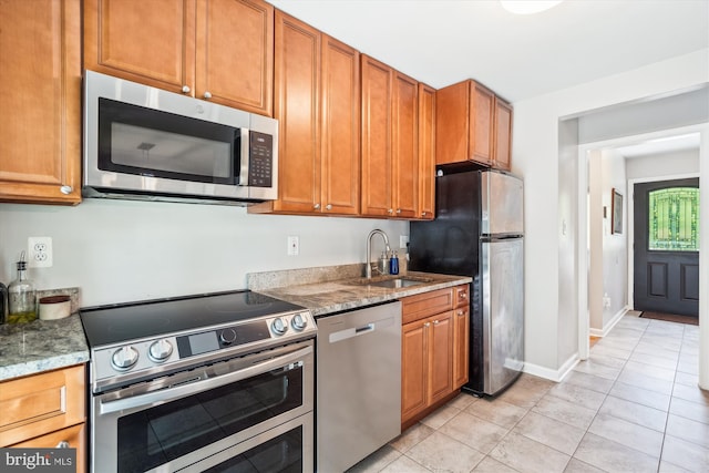 10105 Meredith Ave, Silver Spring, MD 20910 - kitchen featuring stainless steel appliances, a sink, light tile patterned flooring, light stone counters, and brown cabinets